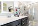 Bathroom with dual sinks, dark cabinets, framed mirrors, and glass-enclosed walk-in shower at 217 Jones Hill Rd, Holly Springs, NC 27540