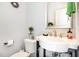 Charming powder room featuring a pedestal sink, decorative mirror and sunburst wall decor at 217 Jones Hill Rd, Holly Springs, NC 27540
