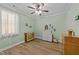 A secondary bedroom with a ceiling fan, wood floors, and a large window at 232 Shady Hollow Ln, Garner, NC 27529