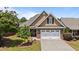 Charming home featuring a two-car garage, stone accents, manicured lawn, and mature trees under a sunny blue sky at 232 Shady Hollow Ln, Garner, NC 27529
