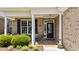 Inviting front porch with brick facade, white columns, black door, and decorative details under a bright covered entryway at 232 Shady Hollow Ln, Garner, NC 27529