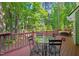 A relaxing back deck with a glass table and chairs surrounded by lush trees at 2408 Fordcrest Dr, Apex, NC 27502