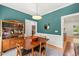 Dining room with teal walls, wood table, and bar cabinet, adjacent to an open staircase at 2408 Fordcrest Dr, Apex, NC 27502
