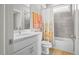 Bright bathroom featuring a floral curtain, tiled walls, white vanity with modern fixtures, and coordinating orange towels at 249 Salt Cedar Ln, Chapel Hill, NC 27516