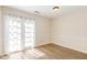 A bedroom with neutral walls, wood-look flooring, and bright lighting through curtained french doors at 2519 Hitchcock Dr, Durham, NC 27705