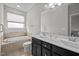Bright bathroom featuring a double vanity, soaking tub, and neutral tile at 256 Rubrum Dr, Hillsborough, NC 27278