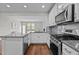 Well-lit kitchen with white cabinets, stainless steel appliances, granite countertops, and a spacious island at 256 Rubrum Dr, Hillsborough, NC 27278