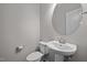 Elegant powder room featuring a pedestal sink and a modern round mirror at 256 Rubrum Dr, Hillsborough, NC 27278