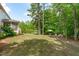 Spacious backyard with lush lawn leading to a wooded area, gazebo, and outdoor seating with a fire pit at 2711 Jordan Pointe Blvd, New Hill, NC 27562