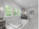 Elegant bathroom featuring a soaking tub, vanity, and a large window at 2711 Jordan Pointe Blvd, New Hill, NC 27562