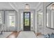 Bright foyer with hardwood floors, a stylish light fixture, and a view of the front yard through the glass-paneled front door at 2711 Jordan Pointe Blvd, New Hill, NC 27562