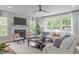Bright living room features a fireplace, a ceiling fan, and a comfortable seating arrangement with large windows at 2711 Jordan Pointe Blvd, New Hill, NC 27562