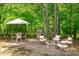 Landscaped backyard featuring a patio with a fire pit, a grill, dining set, and surrounded by lush greenery at 2711 Jordan Pointe Blvd, New Hill, NC 27562