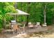 Outdoor patio featuring dining set, grill, and fire pit with seating, perfect for enjoying the wooded backyard at 2711 Jordan Pointe Blvd, New Hill, NC 27562