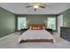 Spacious bedroom featuring a ceiling fan, carpet, a wooden bed frame, and bright natural light at 3003 University Dr, Durham, NC 27707
