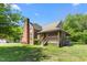 Rear view of a brick home with a chimney, covered porch, and a well-manicured lawn at 319 Knox Rd, Gibsonville, NC 27249