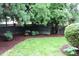 View of the backyard landscaping with a dark wood fence and beautiful shade trees at 3325 Falls River Ave, Raleigh, NC 27614