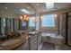 Bright bathroom with double vanity, tub, glass block window, and tiled shower at 3325 Falls River Ave, Raleigh, NC 27614