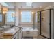 Bright bathroom featuring a soaking tub with tile surround and a glass enclosed shower at 3325 Falls River Ave, Raleigh, NC 27614