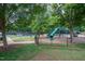 Community playground with a slide and climbing area, nestled in a park-like setting with mature trees and a tennis court at 3325 Falls River Ave, Raleigh, NC 27614