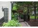 View of the landscaped yard with a wooden pergola, black iron gate, and mature trees at 3325 Falls River Ave, Raleigh, NC 27614