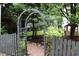 Landscaped backyard with an arched gateway and stone path amid lush greenery and trees at 3325 Falls River Ave, Raleigh, NC 27614