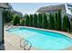Inviting in-ground pool with clear blue water, ladder, and patio furniture with a view of trees and houses at 3536 Greenville Loop Rd, Wake Forest, NC 27587