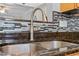Close up of the kitchen sink featuring a dark granite countertop, a silver faucet and a tile backsplash at 510 Berry Chase Way, Cary, NC 27519