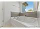 Bright bathroom featuring a large soaking tub under a window, complemented by neutral tile accents at 56 Mable Court # 20, Lillington, NC 27546