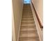 Carpeted staircase featuring a wooden handrail and white trim at 5804 Claribel Ct, Raleigh, NC 27612