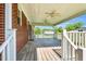 Inviting covered back porch features a wooden deck, ceiling fans, and brick accents at 6080 Us 421 N, Lillington, NC 27546