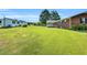 A lush, green backyard is framed by a white shed, large trees, and a brick house at 6080 Us 421 N, Lillington, NC 27546