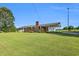 Traditional brick home with a large front yard, covered parking, and mature trees on a sunny day at 6080 Us 421 N, Lillington, NC 27546