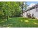 Lush backyard featuring a green lawn, mature trees providing shade, and a home in the background at 619 E Hatterleigh Ave, Hillsborough, NC 27278