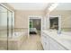 Bathroom showcasing double sinks, a glass shower, and jacuzzi tub with a view into the bedroom at 619 E Hatterleigh Ave, Hillsborough, NC 27278