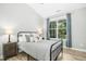 Bright bedroom with a large window, hardwood floors, and a black metal bed frame at 619 E Hatterleigh Ave, Hillsborough, NC 27278