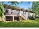 Back exterior of home has green siding, screened porch, stair access, and mature trees at 619 E Hatterleigh Ave, Hillsborough, NC 27278