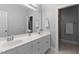 Bright bathroom with double sinks, a large mirror, and a door to a shower with neutral tile at 624 Powhatan Dr, Fuquay Varina, NC 27526