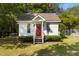 A cozy cottage with a red door, surrounded by lush greenery and a small yard at 624 Powhatan Dr, Fuquay Varina, NC 27526