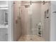Modern shower with a pebble floor, neutral tile, glass door, and wall mounted shelving unit at 624 Powhatan Dr, Fuquay Varina, NC 27526