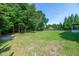 A well-maintained green backyard featuring lush trees, with a partial view of the home and gazebo at 8140 Consella Way, Willow Springs, NC 27592