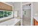Bathroom with a soaking tub under a bright window and an open doorway to the bedroom at 8140 Consella Way, Willow Springs, NC 27592