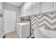 Bright laundry room with white cabinets, chevron wall accents, modern washer and sink at 85 Clubhouse Dr, Youngsville, NC 27596
