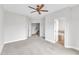 Spacious carpeted bedroom with ceiling fan, view of stairs, and a door to the bathroom at 9211 Calabria Dr # 104, Raleigh, NC 27617