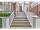 Close up view of wooden and white stairways leading to front door, accented by plants, flower wreaths, and brick features at 9211 Calabria Dr # 104, Raleigh, NC 27617