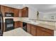 Well-equipped kitchen features granite countertops, brown cabinetry, and modern black appliances at 9211 Calabria Dr # 104, Raleigh, NC 27617