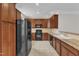 Efficient kitchen featuring rich wood cabinetry, a full suite of black appliances, and tiled floors, ideal for cooking at 9211 Calabria Dr # 104, Raleigh, NC 27617