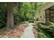 Stone paver walkway through a lush landscaped backyard with mature trees at 1007 Surry Dale Ct, Apex, NC 27502