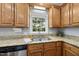 Kitchen sink area with wood cabinets, granite countertops, and backyard view at 1007 Surry Dale Ct, Apex, NC 27502