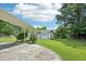 View of the detached garage and carport surrounded by lush greenery at 102 Pine St, Dunn, NC 28334